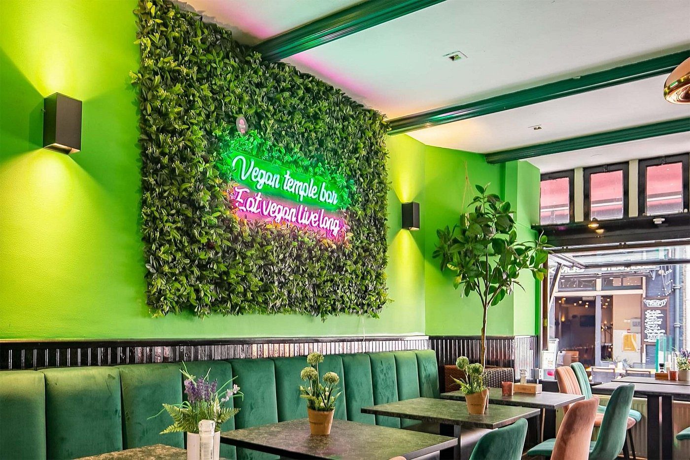 Verlicht 'Eat vegan live long' bord op de plantenwand